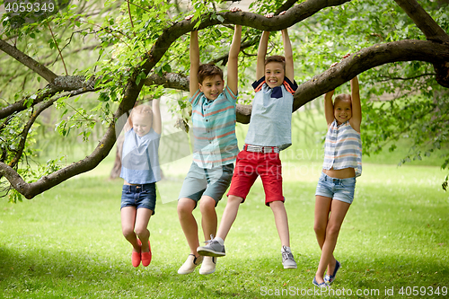 Image of happy kids hanging on tree in summer park