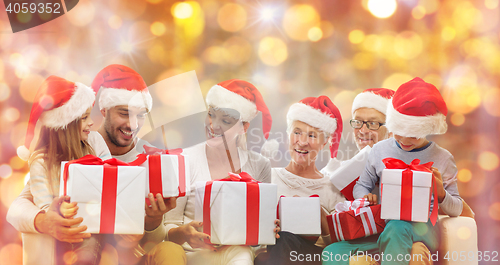 Image of happy family in santa hats with gift boxes