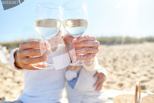 Image of happy senior couple drinking wine on summer beach
