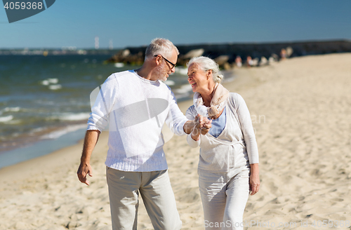 Image of happy senior couple holding hands on summer beach