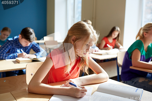 Image of student girl with book writing school test