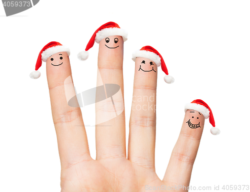 Image of close up of hand with four fingers in santa hats