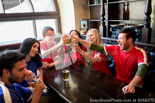 Image of football fans clinking beer glasses at sport bar