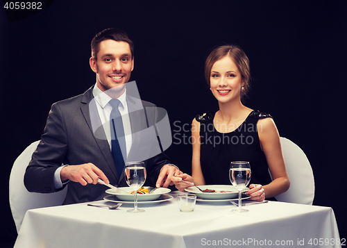 Image of smiling couple eating main course at restaurant