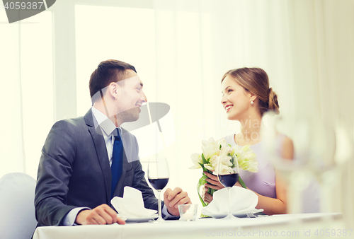 Image of smiling man giving flower bouquet at restaurant