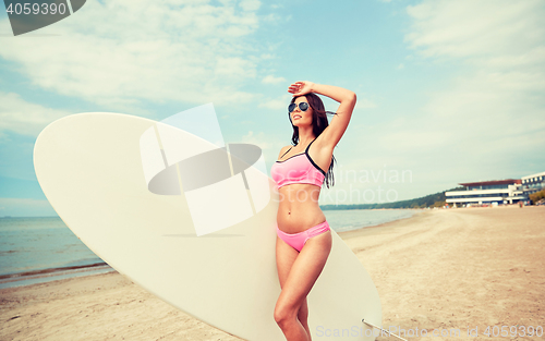 Image of smiling young woman with surfboard on beach