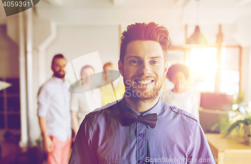 Image of happy young man over creative team in office