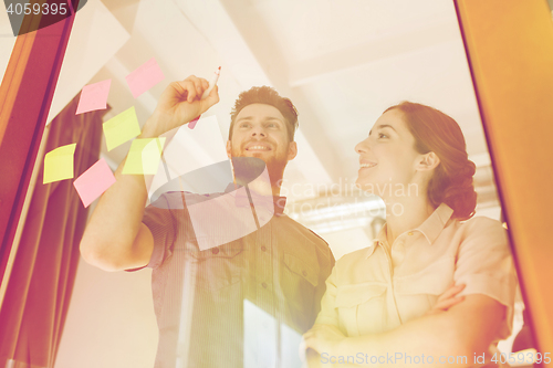 Image of happy creative team writing on blank office glass