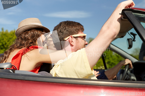 Image of happy friends driving in cabriolet car at country