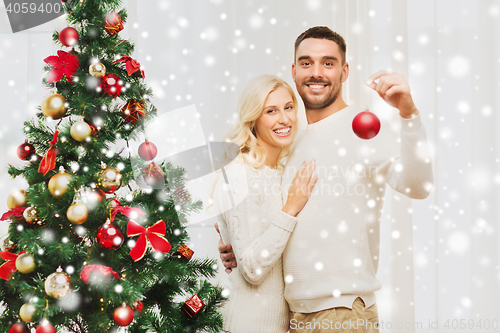 Image of happy couple decorating christmas tree at home