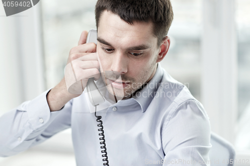 Image of face of businessman calling on phone in office