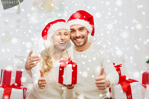 Image of happy couple with christmas gifts and thumbs up