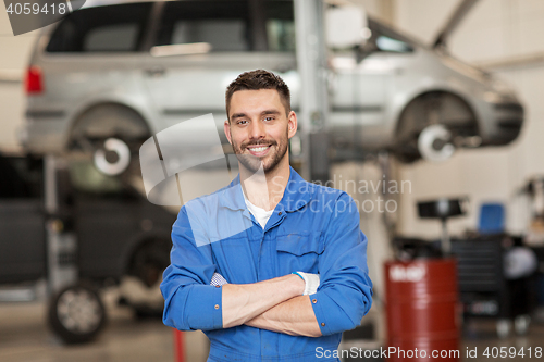 Image of happy auto mechanic man or smith at car workshop