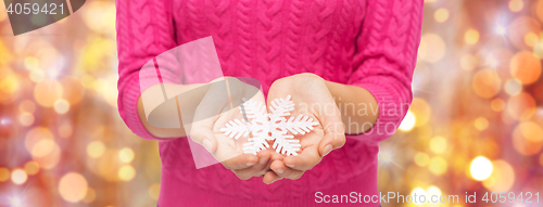 Image of close up of woman in sweater holding snowflake