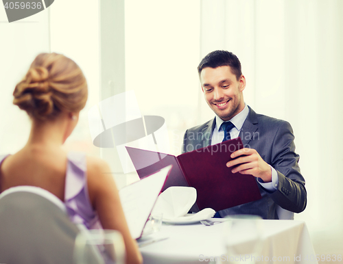 Image of smiling young man looking at menu at restaurant