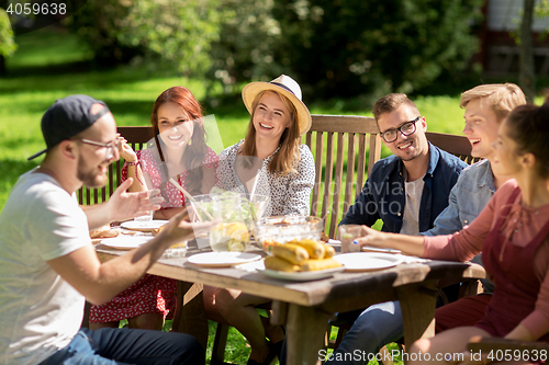 Image of happy friends having dinner at summer garden party