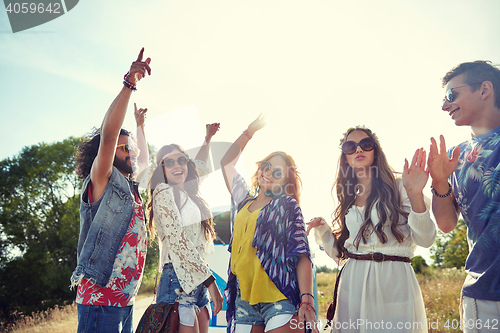 Image of happy young hippie friends dancing outdoors