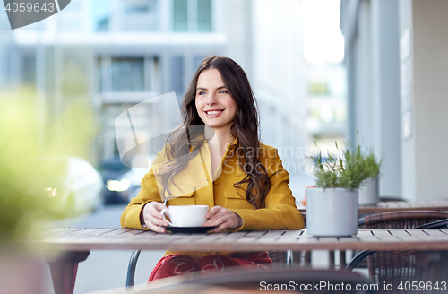 Image of happy woman drinking cocoa at city street cafe