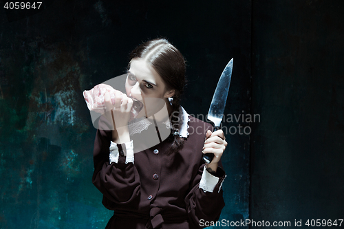 Image of Bloody Halloween theme: crazy girl with a knife and raw meat