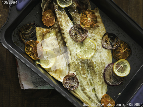 Image of cooked sea bass with lemon, onion and tomato ready