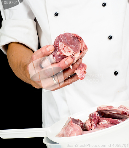 Image of A professional chef in jacket, holding a lump of red meat