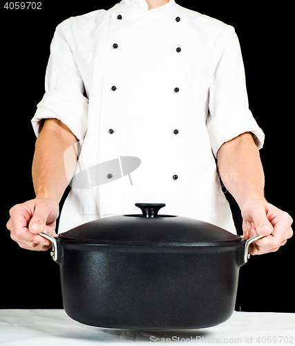 Image of Chef holding a casserole towards, over white table clothing on b