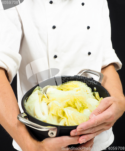 Image of Chef in white jacket holding around a casserole of boiled cabbag