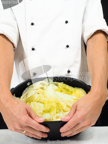 Image of Chef in white jacket holding around a casserole of boiled cabbag