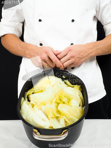 Image of Chef in white jacket holding around a casserole of boiled cabbag