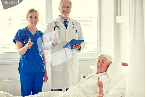 Image of doctor and nurse visiting senior woman at hospital