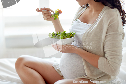 Image of close up of pregnant woman eating salad at home