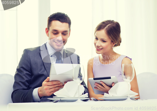 Image of couple with menus on tablet pc at restaurant