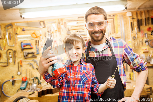 Image of father and son with drill working at workshop