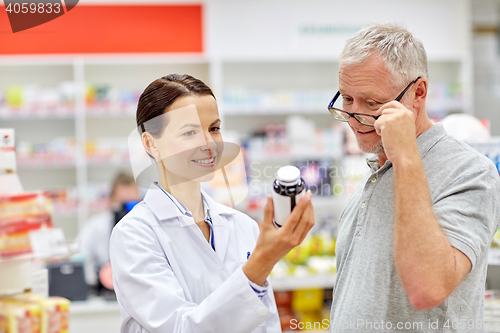 Image of pharmacist showing drug to senior man at pharmacy