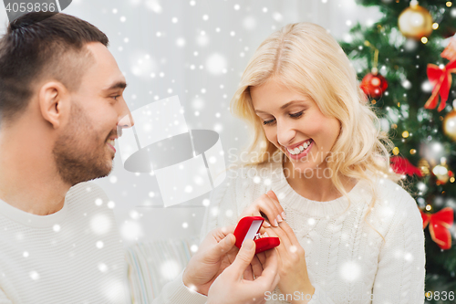 Image of man giving woman engagement ring for christmas