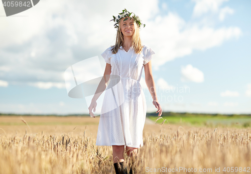 Image of happy young woman in flower wreath on cereal field