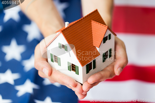 Image of close up of hands holding house over american flag