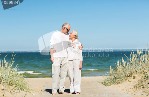 Image of happy senior couple hugging on summer beach