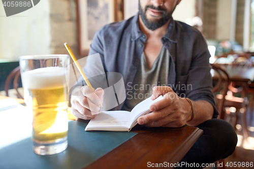 Image of close up of man with beer and notebook at pub