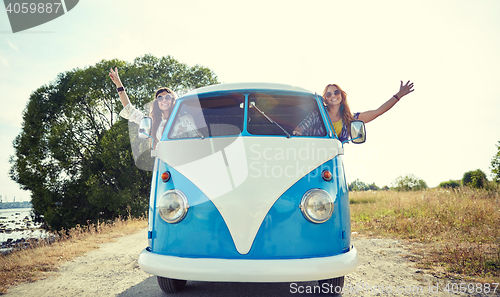 Image of smiling young hippie women driving minivan car