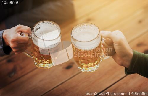 Image of close up of hands with beer mugs at bar or pub