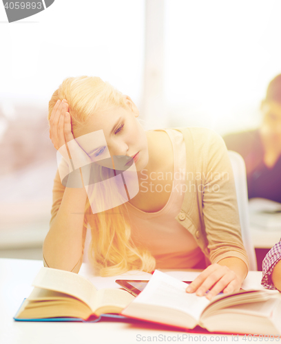 Image of tired teenage student with tablet pc and books