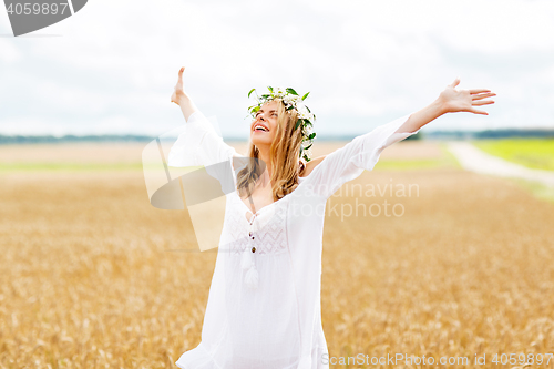 Image of happy young woman in flower wreath on cereal field