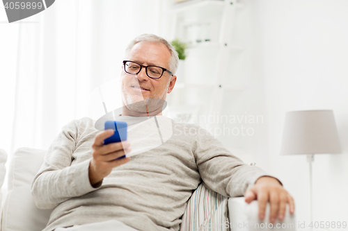 Image of happy senior man texting on smartphone at home