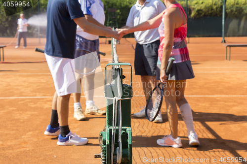 Image of Mixed doubles tennis players shake hands before and after the te