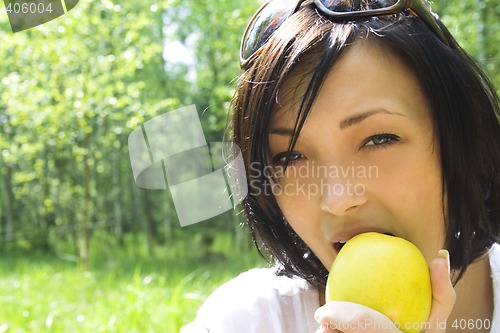 Image of young happy woman eating apple