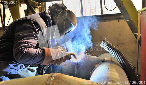 Image of woman welder welding