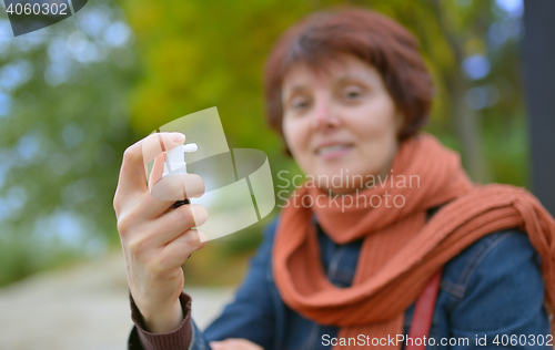 Image of Young woman using throat spray 