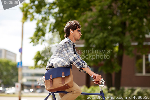 Image of young hipster man with bag riding fixed gear bike