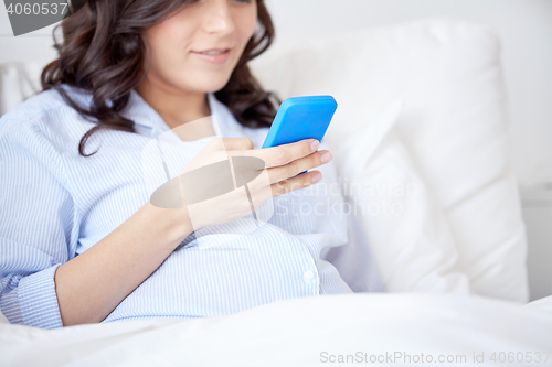 Image of close up of pregnant woman with smartphone in bed